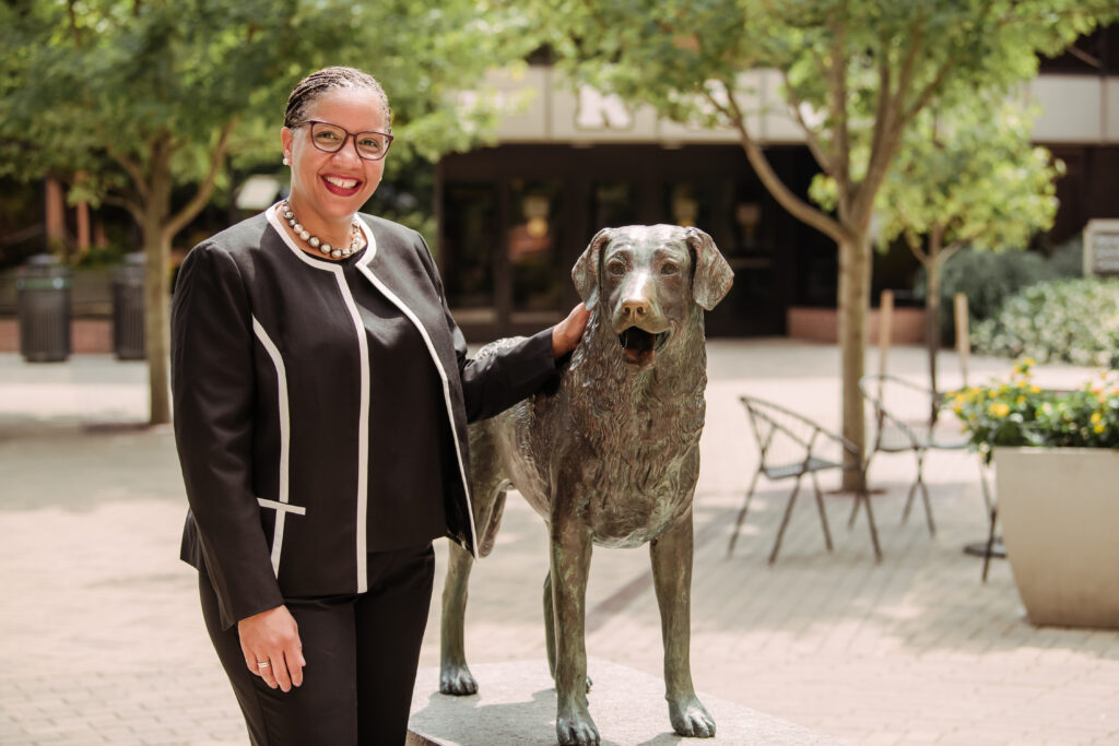 Dr. Renique Kersh placing a hand on the True Grit statue on Academic Row.