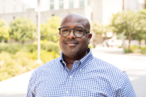 David Goode-Cross outside on UMBC's campus in a plaid shirt